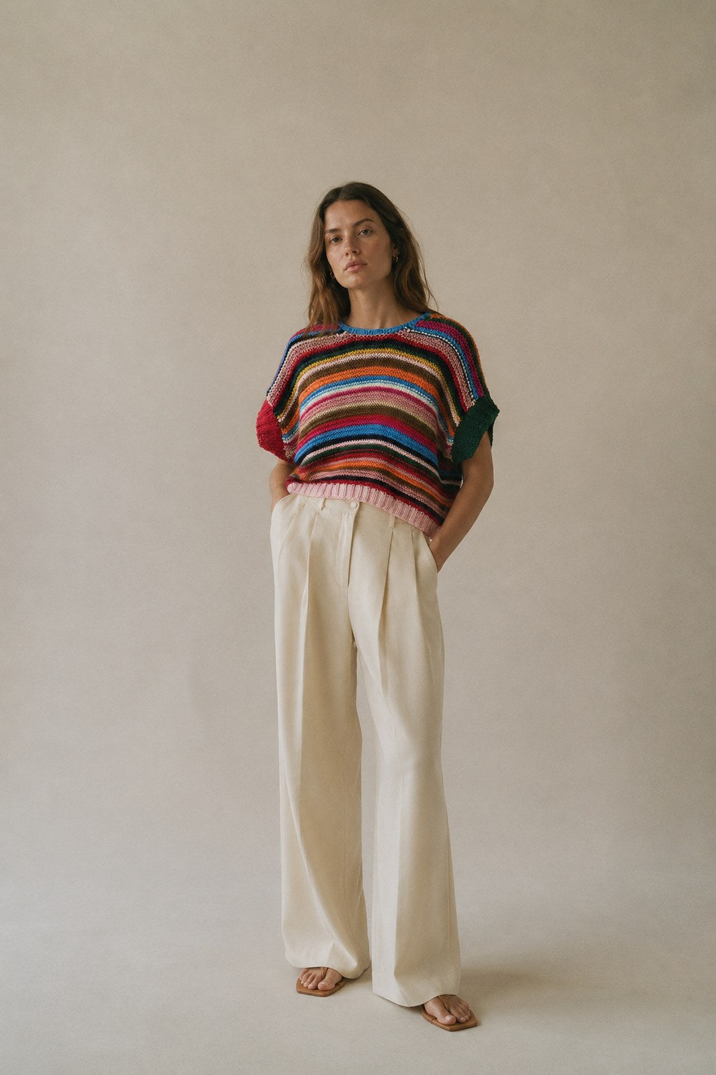 Modella indossa il gilet a righe multicolor con pantaloni avorio a gamba larga, figura intera - Studio Gugu